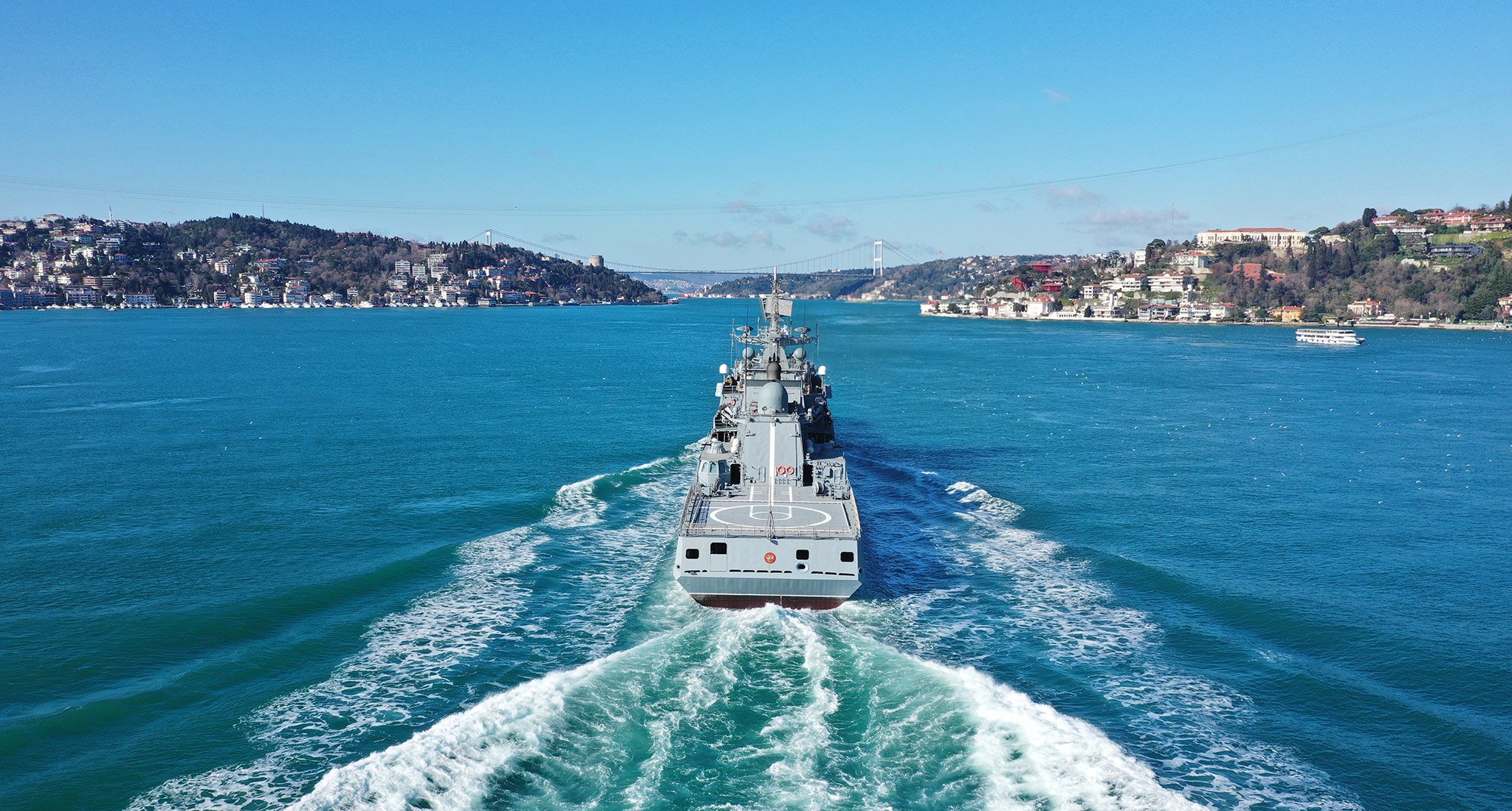Image of naval ship at sea with city in background