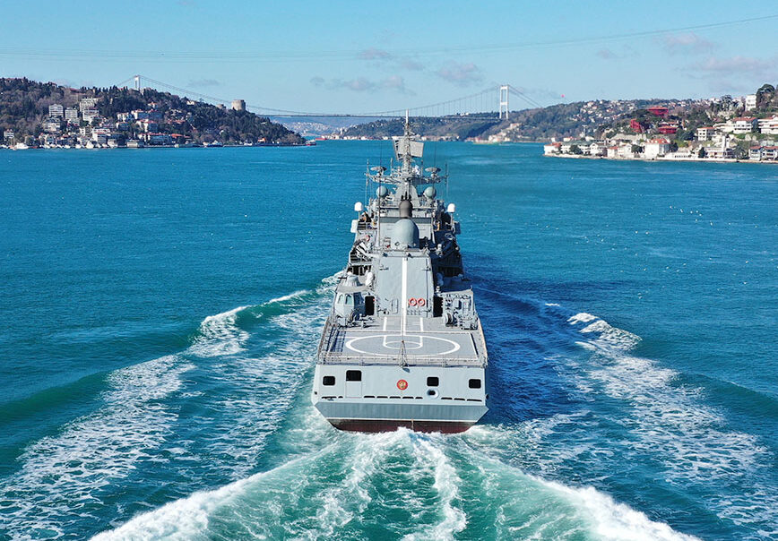 Image of naval ship at sea with city in the background