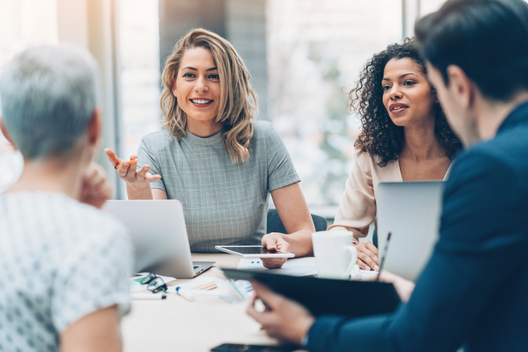 A group of professionals having a collaborative business meeting around a table with laptops in a bright modern office